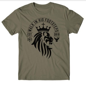 May include: A green t-shirt with a black lion head graphic. The graphic includes a crown, a cross, and the text "Walk in His Footsteps Est. 2018".