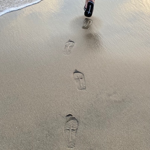 Op de afbeelding: Voetafdrukken in het zand met een kruisontwerp op de zolen van de schoenen.