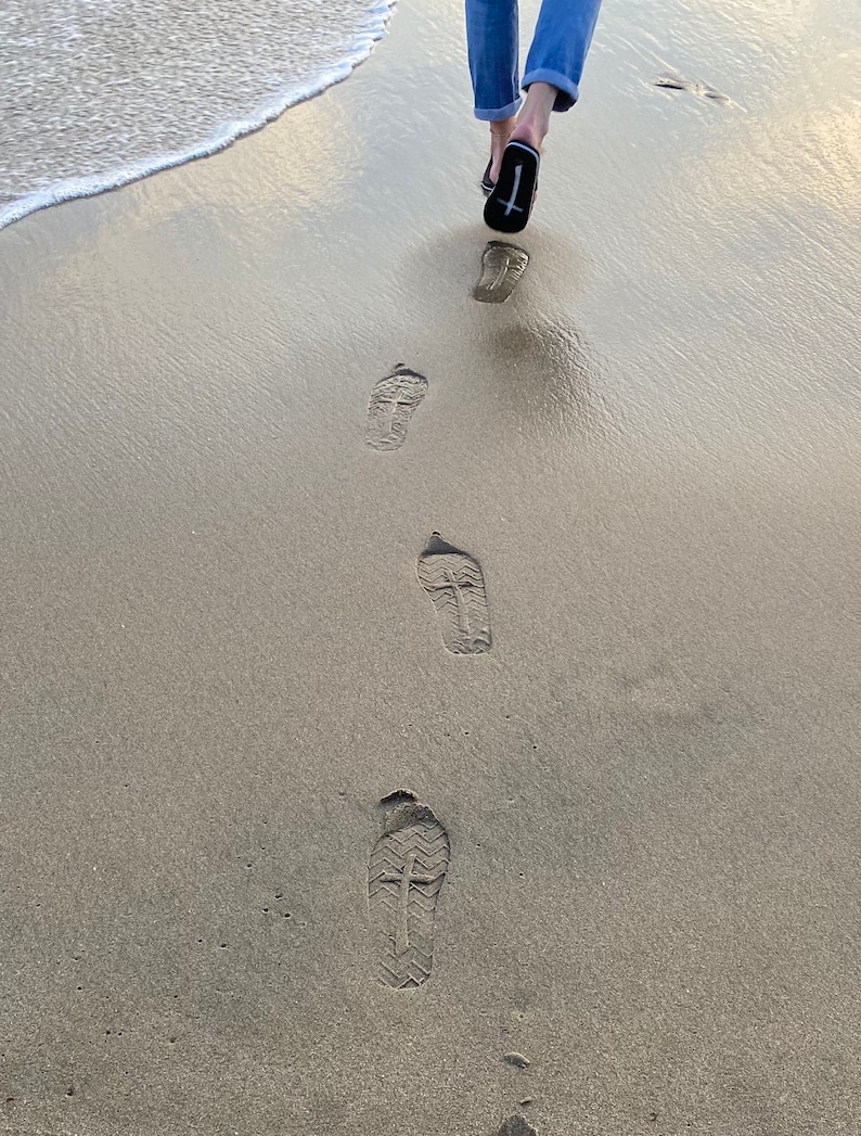 Op de afbeelding: Voetafdrukken in het zand met een kruisontwerp op de zolen van de schoenen.