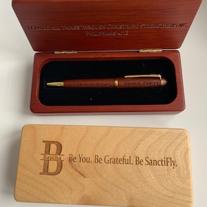 May include: A wooden pen with gold accents engraved with COALDUST BOOKS and DAVID K. FARLEY, resting in a dark wood case with the engraved text I CAN DO ALL THINGS THROUGH CHRIST WHO STRENGTHENS ME. PHILIPPIANS 4:13, beside a light wood box lid.