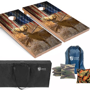 May include: Two wooden cornhole boards with an American flag and a deer design. The boards are set up for a game of cornhole. The set includes a carrying bag, bean bags, and a set of cornhole boards.