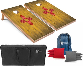 May include: A set of two wooden cornhole boards with a New Mexico flag design. The boards are yellow with red and white accents. The set includes a black carrying bag, a blue drawstring bag, and eight bean bags: four red and four gray.