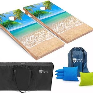 May include: Two wooden cornhole boards with a beach scene and palm trees. The boards are on a white background. There is a black carrying bag, a blue drawstring bag with the text "Tailgating Pros", and six bean bags in blue and green.