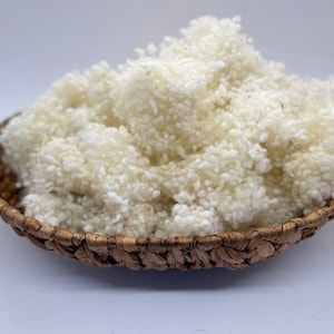 May include: A close-up of a basket filled with white cotton fibre. The cotton is fluffy and soft, and it is perfect for crafting or filling cushions.