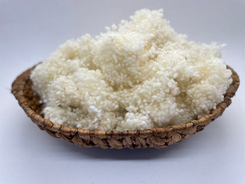 May include: A close-up of a basket filled with white cotton fibre. The cotton is fluffy and soft, and it is perfect for crafting or filling cushions.