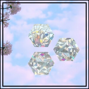 May include: Three iridescent hexagonal stickers with a stained glass pattern. The stickers are on a light blue and pink background with white clouds.