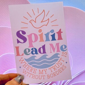 May include: A rectangular white card featuring a graphic design with a dove icon at the top. The text reads Spirit Lead Me in colourful letters, followed by the phrase Where My Trust Is Without Borders in a curved layout above blue waves.