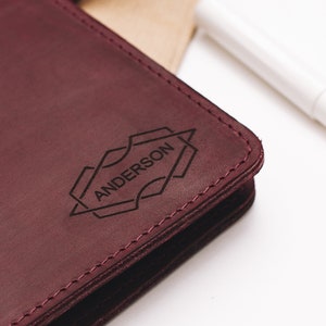 May include: A burgundy leather journal with the name "ANDERSON" embossed in a geometric design.