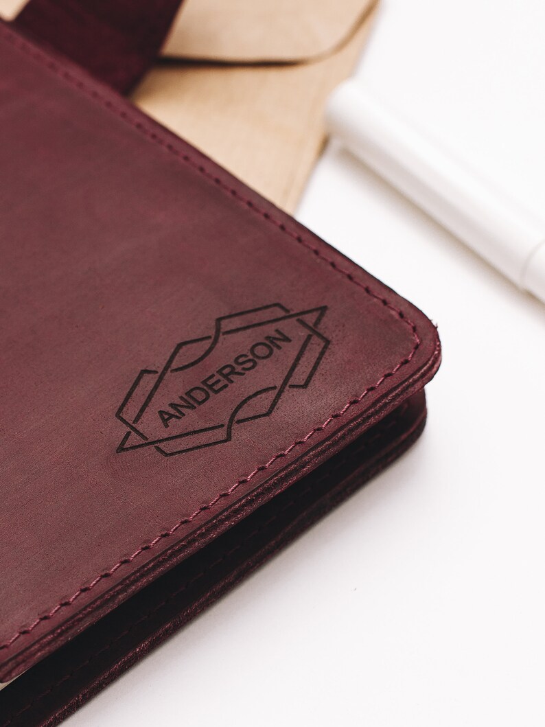 May include: A burgundy leather journal with the name "ANDERSON" embossed in a geometric design.