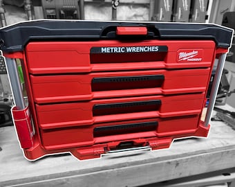 Può includere: Scatola portautensili Milwaukee Packout rossa con cinque cassetti e una maniglia nera. Il cassetto superiore ha un'etichetta che dice "Chiavi metriche".