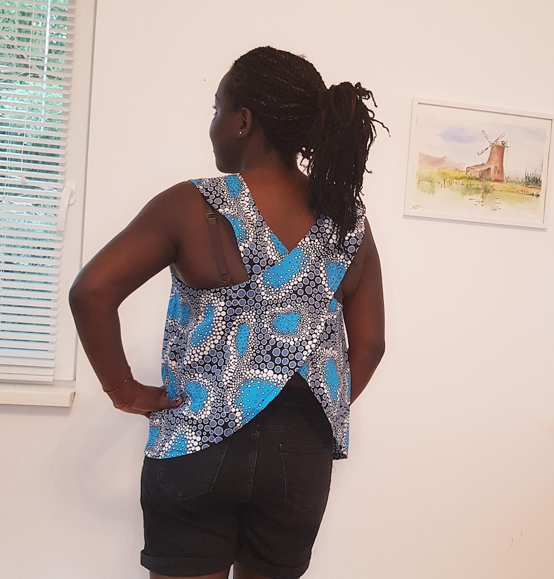 May include: A sleeveless top with a blue and white patterned design. The top has a criss-cross back detail and a high neckline.