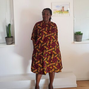 May include: A red, yellow, and black patterned dress with a mandarin collar and short sleeves.