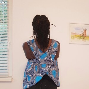 May include: A sleeveless top with a blue and white patterned design. The back of the top features a criss-cross design.