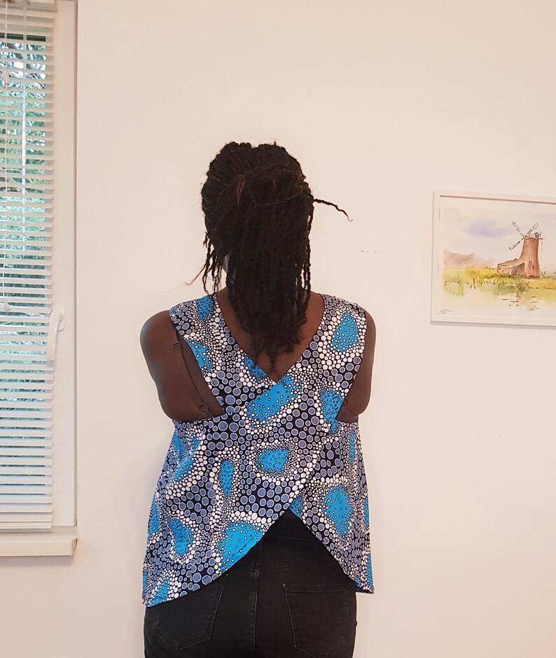 May include: A sleeveless top with a blue and white patterned design. The back of the top features a criss-cross design.