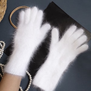 May include: A pair of white fluffy long gloves. The gloves are made of a soft, fluffy material and have a long, slender design.