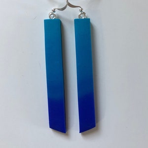 Peut inclure: Une paire de boucles d'oreilles pendantes bleu dégradé avec des crochets argentés. Les boucles d'oreilles sont en pâte polymère et présentent un dégradé du bleu clair au bleu foncé.