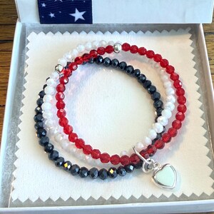 3 bracelets made with the 3 crystal USA flag colors and joined with a sterling silver heart charm in a jewelry box