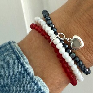 A wrist with the USA 3 colors bracelet made with 3 separate bracelets joined with a sterling silver heart charm