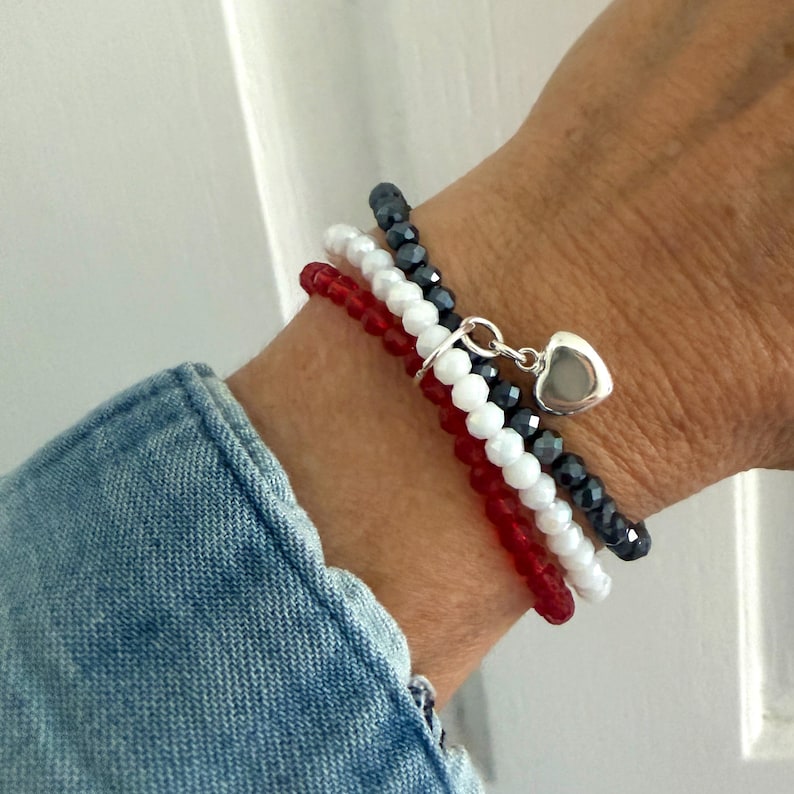 A wrist with the USA 3 colors bracelet made with 3 separate bracelets joined with a sterling silver heart charm