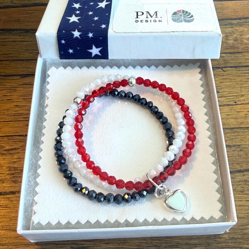 3 bracelets made with the 3 crystal USA flag colors and joined with a sterling silver heart charm in a jewelry box