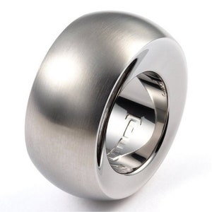 May include: A silver ring with a smooth, rounded surface. The ring is made of metal and has a polished finish.