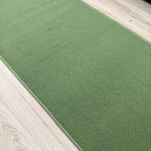 May include: A rectangular area rug featuring a solid sage green color with a dense, short-pile texture. The rug has finished, matching green edges and a clean, uniform surface appearance that covers the majority of the visible frame.