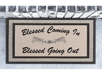 May include: A brown doormat with a beige background and black text that reads "Blessed Coming In" with a floral design and "Blessed Going Out".