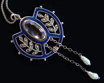 May include: A silver pendant necklace with a blue enamel and amethyst centerpiece. The pendant features a geometric design with a floral motif and two dangling pearls.