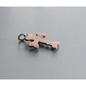 May include: A silver cross pendant with a detailed design. The cross is made of small, interconnected circles.