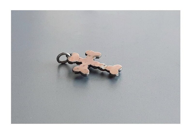 May include: A silver cross pendant with a detailed design. The cross is made of small, interconnected circles.