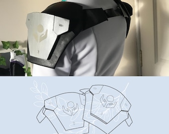 May include: A set of shoulder armor pieces featuring a black base with silver metallic plates, each displaying a central emblem of two hands cradling a circle. The image includes a white shirt, a teal collar, and a line art PDF pattern illustration.
