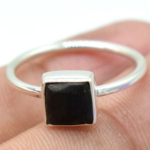 Puede incluir: Un anillo de plata con una piedra negra cuadrada.