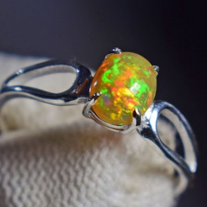 Op de afbeelding: Een zilveren ring met een groene, oranje en rode opaal edelsteen.