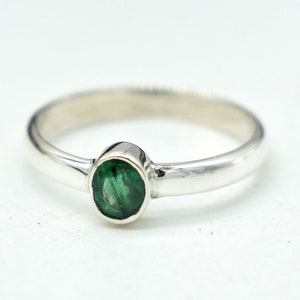 May include: A silver ring with a green emerald gemstone.