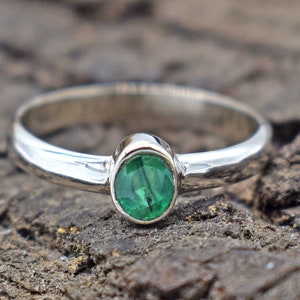 May include: A silver ring with a green oval gemstone.