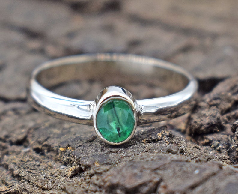 May include: A silver ring with a green oval gemstone.