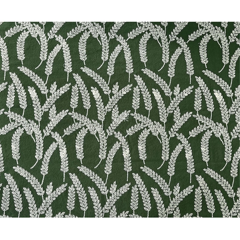 May include: A green fabric with a white floral pattern. The pattern is a repeating design of small white sprigs.
