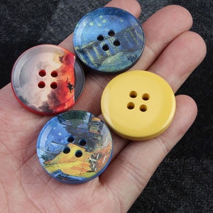 以下が含まれることがあります： 異なるデザインの丸いボタンが4つあります。2つのボタンは、夜空のシーンが描かれた青と黄色のデザインです。1つのボタンは、夕焼けのシーンが描かれた赤とオレンジです。最後のボタンは黄色です。