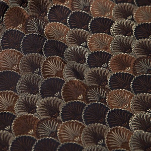 May include: A brown and black fabric with a repeating pattern of stylized fans. The fabric has a textured, woven look.
