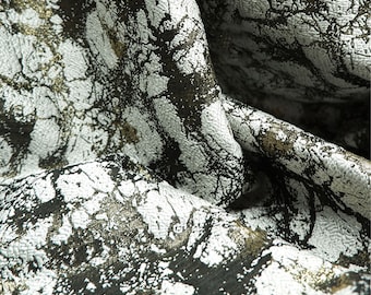 May include: Close-up of a textured fabric with a marbled pattern. The fabric features a combination of white, black, and gold colors. The design has a cracked, organic appearance, creating a unique visual texture. The fabric is likely used for apparel or home decor.