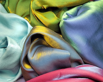 May include: A close-up of a pile of iridescent fabric in various shades of green, blue, and red. The fabric has a subtle shimmer and a smooth texture.