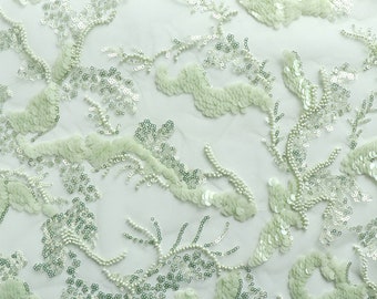 May include: Pale green fabric with a delicate pattern of sequins and beads. The fabric has a sheer, mesh-like texture.