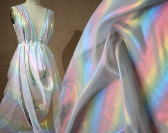 May include: White iridescent fabric with a rainbow sheen. The fabric is sheer and has a soft, flowing texture.
