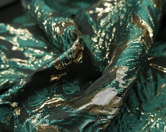 May include: Green fabric with a gold metallic floral pattern. The fabric has a textured, woven look.
