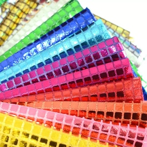 Könnte beinhalten: Eine Regenbogen-Auswahl an schimmernden Stoffen mit quadratischem Muster. Der Stoff ist glänzend und reflektierend, mit Farben von Gold bis Blau.