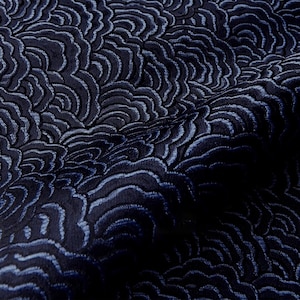 Puede incluir: Primer plano de una tela azul marino con un patrón repetitivo en forma de ola. El diseño presenta una superficie texturizada con acentos azul claro, creando una sensación de profundidad y movimiento. La tela parece ser un material lujoso, posiblemente para tapicería o ropa.