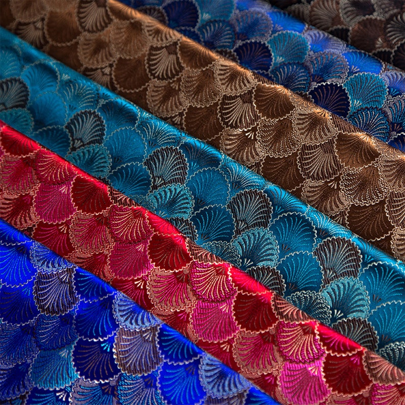 May include: Close-up of five fabric swatches with a geometric pattern of overlapping fan shapes. The swatches are in shades of blue, red, brown, and teal.