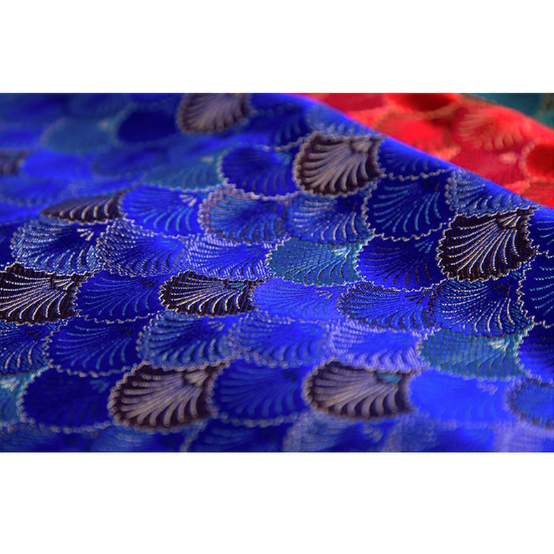 May include: Blue fabric with a repeating pattern of silver and black seashells. The fabric has a textured, woven look.