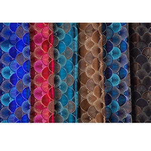 May include: Close-up of six fabric swatches with a repeating pattern of overlapping, stylized, fan-shaped designs. The swatches are in shades of blue, red, teal, brown, and navy.