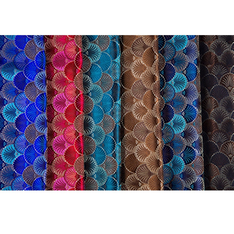 May include: Close-up of six fabric swatches with a repeating pattern of overlapping, stylized, fan-shaped designs. The swatches are in shades of blue, red, teal, brown, and navy.
